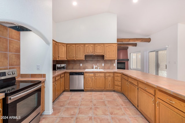 kitchen featuring tile countertops, lofted ceiling with beams, sink, light tile patterned floors, and stainless steel appliances