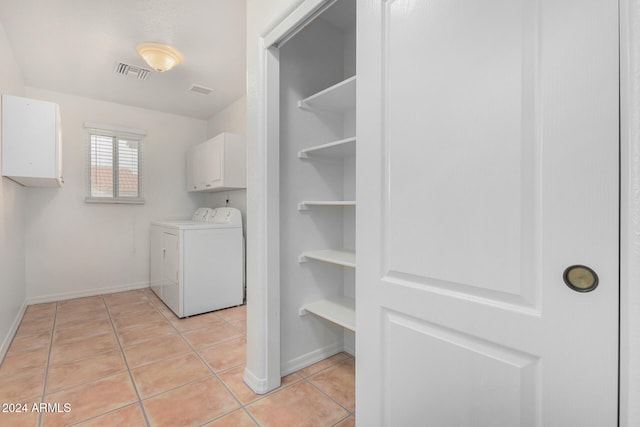 clothes washing area with cabinets, washing machine and dryer, and light tile patterned flooring