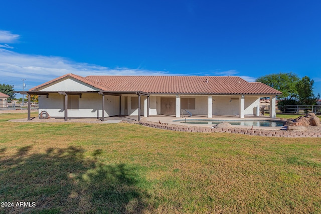 rear view of property featuring a lawn, a patio area, and an in ground hot tub