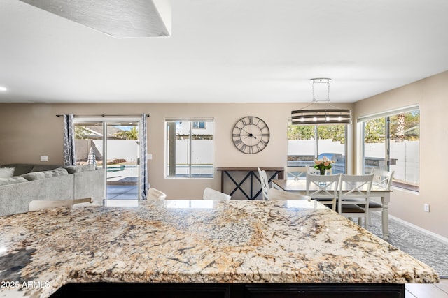 kitchen with open floor plan, pendant lighting, baseboards, and light stone countertops