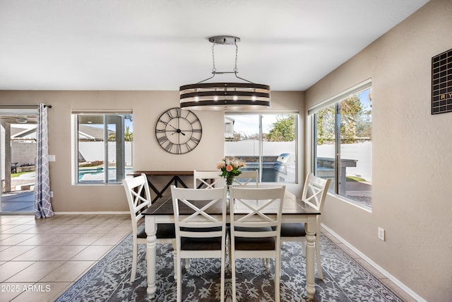 tiled dining space with baseboards and a healthy amount of sunlight