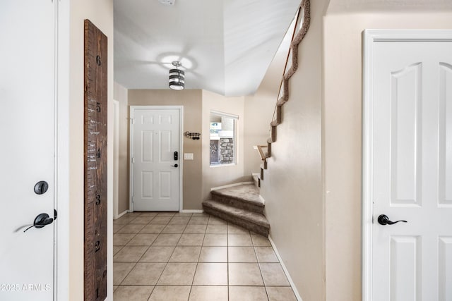 entryway featuring stairway, light tile patterned flooring, and baseboards