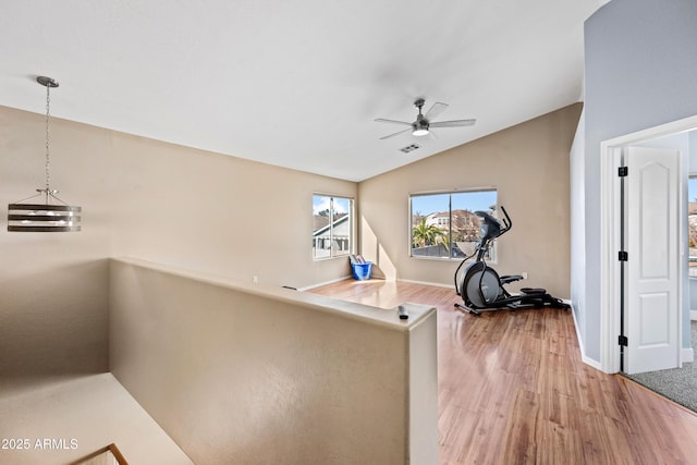 exercise area featuring baseboards, visible vents, a ceiling fan, wood finished floors, and vaulted ceiling