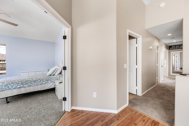 hallway featuring carpet floors, wood finished floors, and baseboards