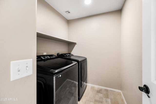 laundry area featuring laundry area, baseboards, visible vents, washing machine and clothes dryer, and light wood-style floors