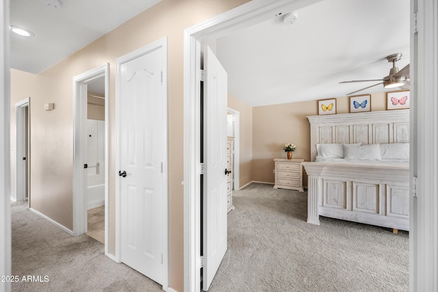 bedroom with light colored carpet, vaulted ceiling, and baseboards