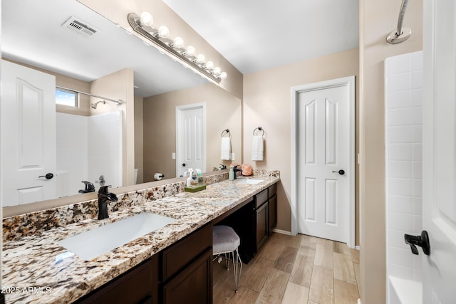 bathroom with double vanity, wood finished floors, a sink, and visible vents