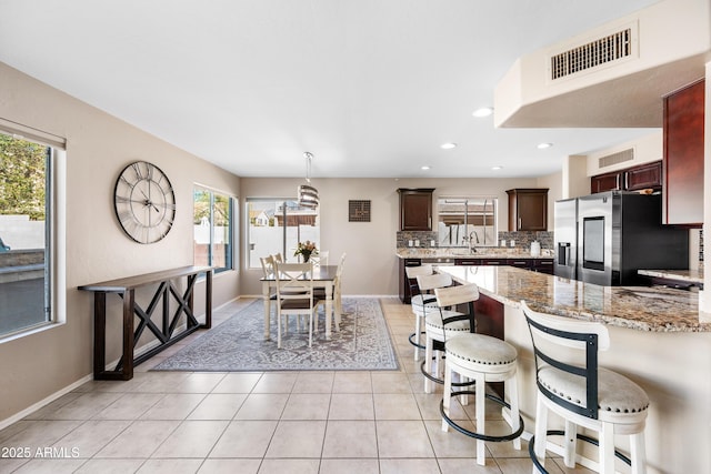 kitchen with stainless steel fridge, tasteful backsplash, visible vents, a peninsula, and a sink