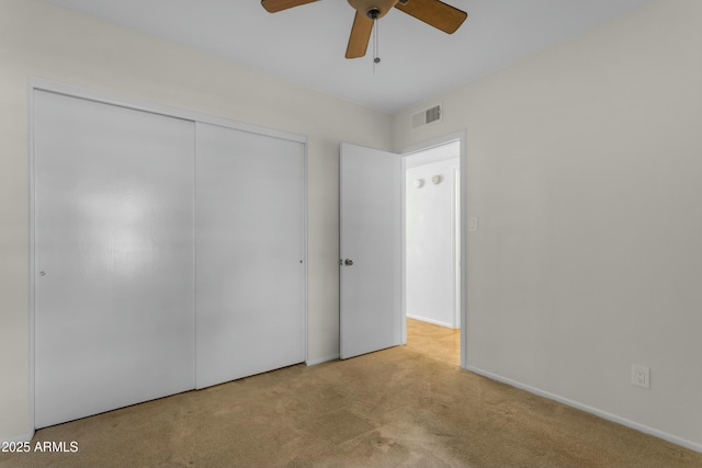 unfurnished bedroom with ceiling fan, a closet, and light carpet