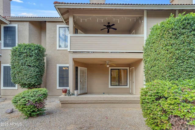 entrance to property with ceiling fan and a balcony