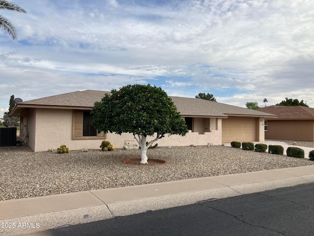 ranch-style house featuring a garage, central AC unit, concrete driveway, and stucco siding