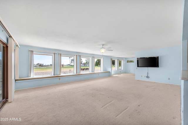 unfurnished living room featuring light carpet and a ceiling fan