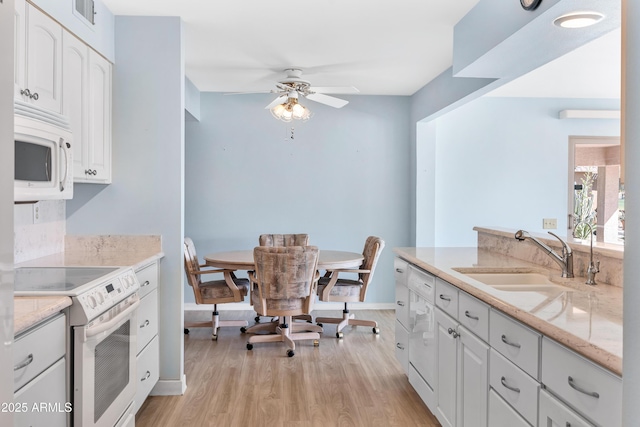 kitchen featuring white appliances, a sink, white cabinetry, and light wood-style floors