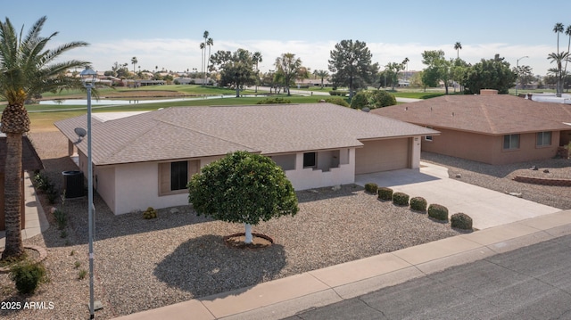 single story home with cooling unit, a water view, driveway, roof with shingles, and stucco siding