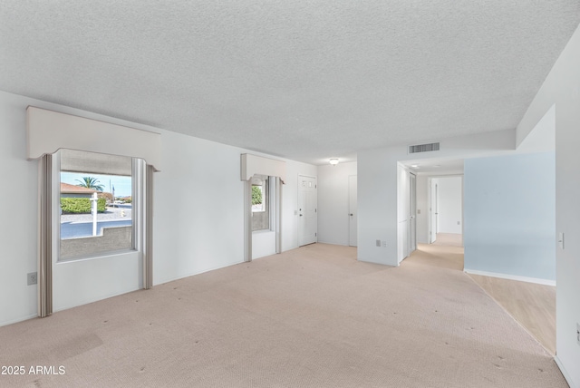 unfurnished room featuring visible vents, light carpet, and a textured ceiling