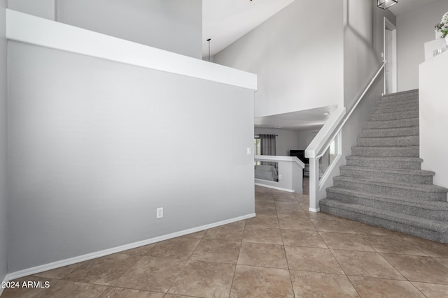 staircase featuring tile patterned flooring and a towering ceiling