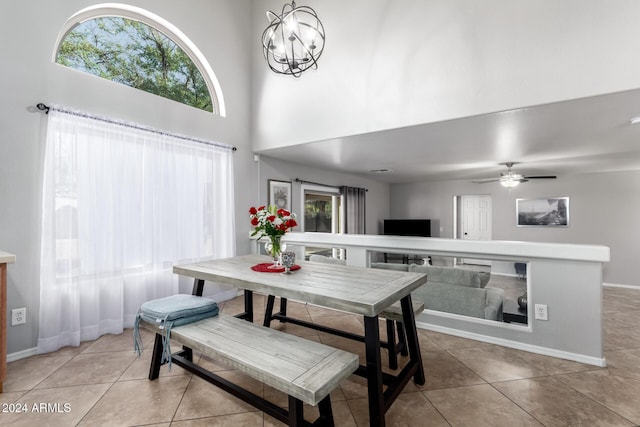 dining area featuring a high ceiling, ceiling fan with notable chandelier, and light tile patterned flooring