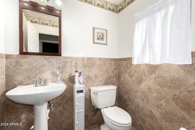 bathroom featuring toilet and tile walls