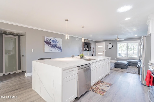 kitchen featuring appliances with stainless steel finishes, a center island with sink, white cabinets, and light stone counters