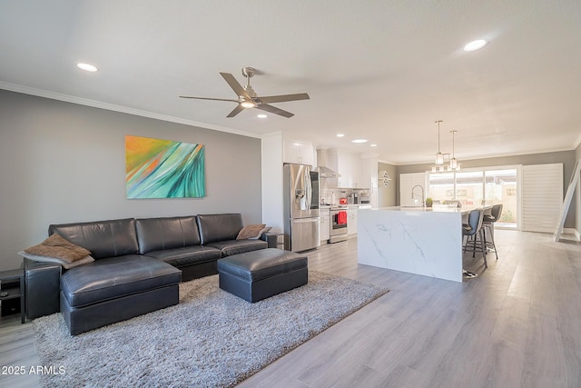 living room with sink, crown molding, light hardwood / wood-style floors, and ceiling fan