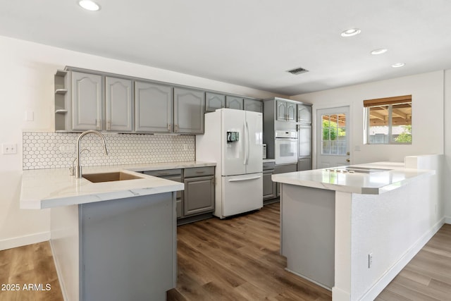 kitchen with gray cabinetry, a peninsula, and white appliances