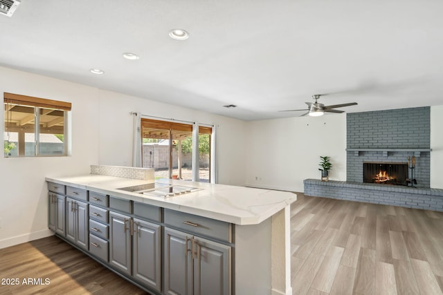 kitchen with ceiling fan, light wood-type flooring, gray cabinetry, a peninsula, and electric cooktop