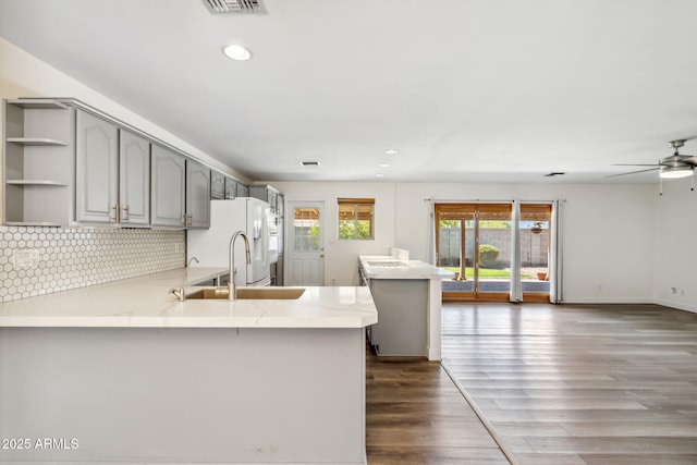 kitchen featuring open shelves, a peninsula, ceiling fan, gray cabinets, and white fridge with ice dispenser