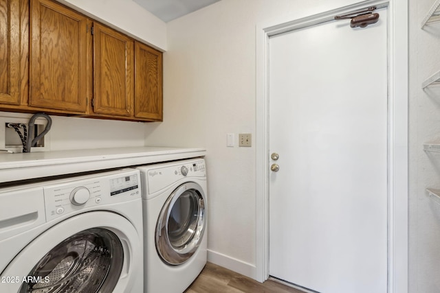 laundry room with baseboards, light wood-style flooring, cabinet space, and washing machine and dryer