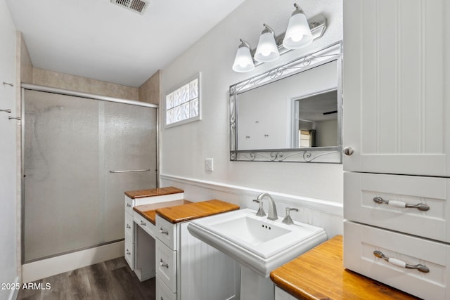 full bath featuring a sink, visible vents, a shower stall, and wood finished floors