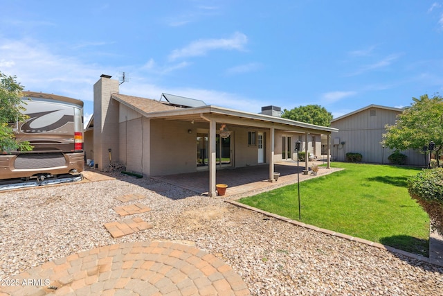 rear view of property with a lawn, a patio, and a chimney