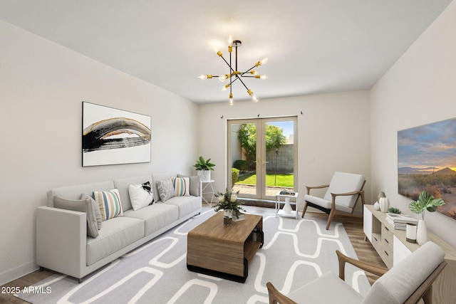 living area featuring baseboards, french doors, wood finished floors, and a chandelier