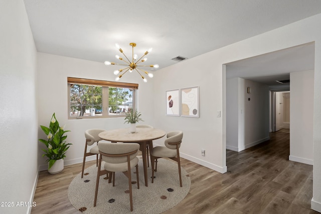 dining area featuring baseboards, a notable chandelier, wood finished floors, and visible vents