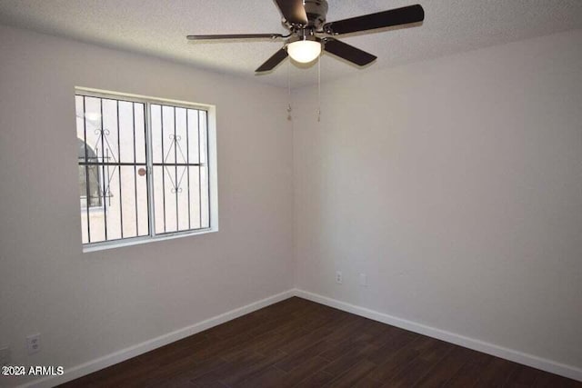 empty room featuring plenty of natural light, ceiling fan, and dark wood-type flooring