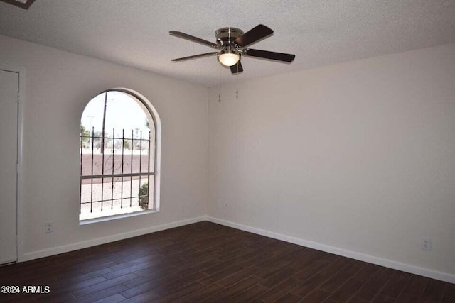 empty room with ceiling fan, a textured ceiling, and dark wood-type flooring