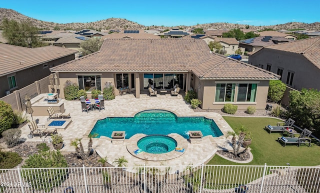 view of swimming pool with a yard, an outdoor fire pit, a patio area, a mountain view, and an in ground hot tub