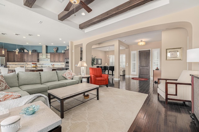 living room with hardwood / wood-style flooring, ceiling fan, and beam ceiling