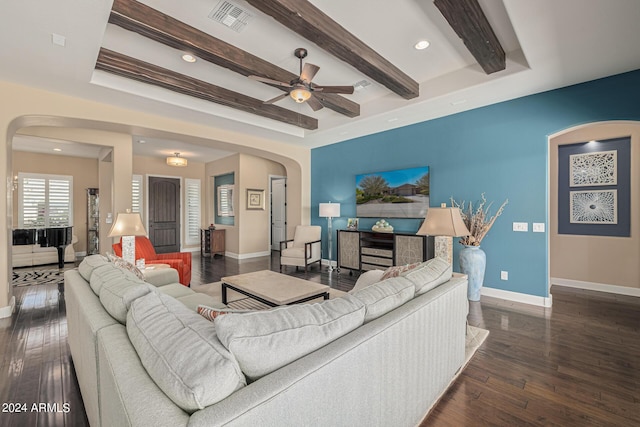 living room with beam ceiling, dark wood-type flooring, a raised ceiling, and ceiling fan