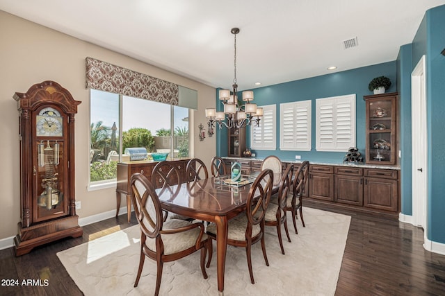 dining area with dark hardwood / wood-style floors and an inviting chandelier