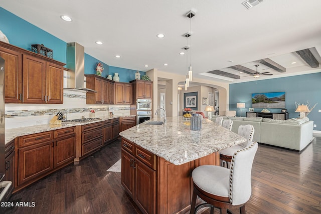 kitchen featuring pendant lighting, ventilation hood, dark hardwood / wood-style flooring, a kitchen breakfast bar, and a spacious island