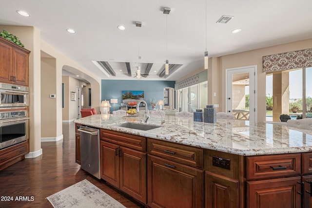 kitchen with sink, hanging light fixtures, a large island with sink, dark hardwood / wood-style floors, and stainless steel appliances