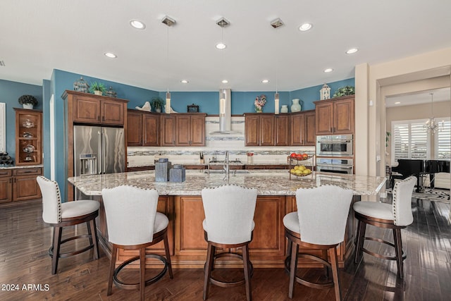 kitchen with a large island, pendant lighting, light stone countertops, and appliances with stainless steel finishes