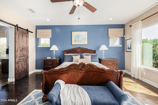 bedroom with dark hardwood / wood-style floors, ceiling fan, and a barn door