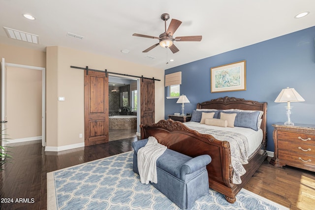 bedroom with dark hardwood / wood-style floors, a barn door, ceiling fan, and ensuite bathroom