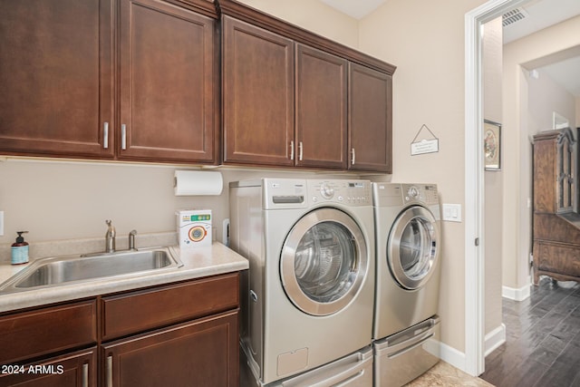 washroom with dark hardwood / wood-style flooring, sink, cabinets, and washing machine and clothes dryer