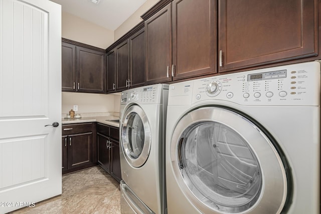 clothes washing area with cabinets and washing machine and clothes dryer