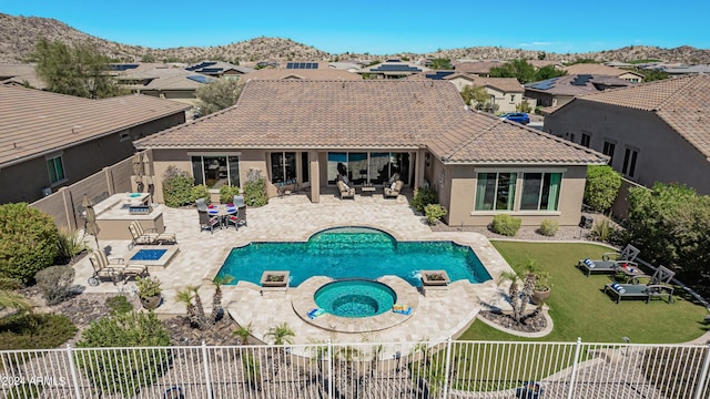 exterior space with a yard, an outdoor fire pit, a patio area, a mountain view, and an in ground hot tub