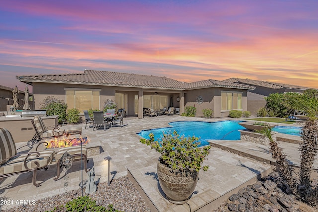 pool at dusk with a patio and a fire pit