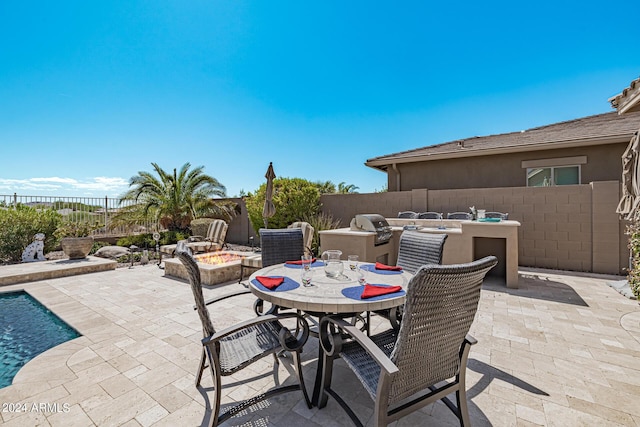 view of patio featuring area for grilling, a fire pit, and exterior kitchen