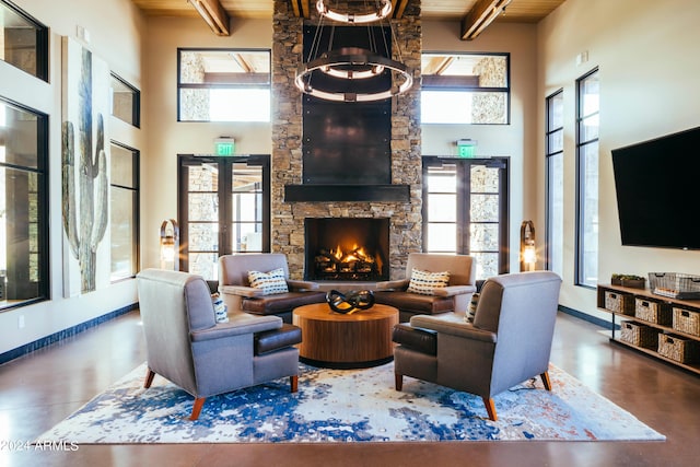 living room featuring beamed ceiling, a stone fireplace, a high ceiling, and french doors