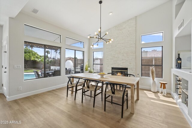 19203 N 39th Way, Phoenix, AZ 85050 - dining area with high vaulted ceiling, visible vents, a stone fireplace, a chandelier, and light wood finished floors